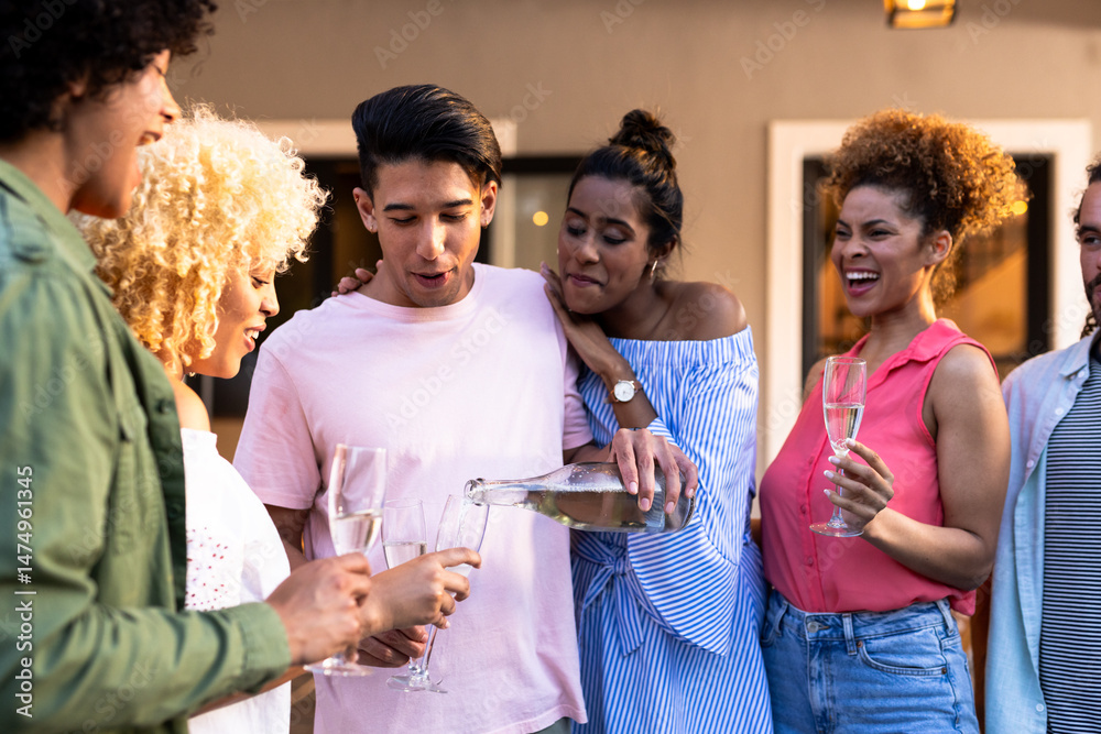 Obraz premium Young Diverse friends enjoying outdoor gathering, pouring champagne and laughing together