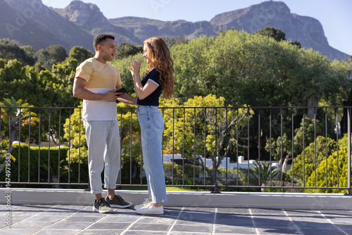 Panel kuchenny z motywem Young couple enjoying conversation on sunny balcony with scenic mountain view