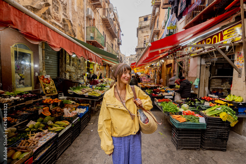 Obraz premium A woman in a yellow jacket strolls through a vibrant local market in Sicily, surrounded by fresh produce. The image conveys authentic travel, cultural immersion, and slow lifestyle 