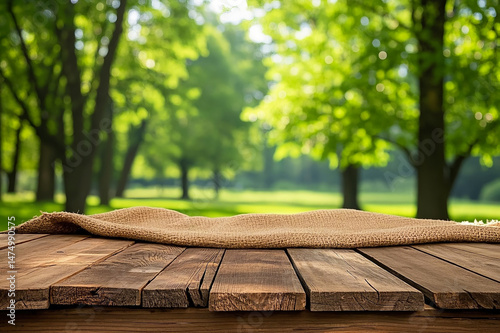 Nature background with empty wooden table and sack tablecloth, ideal for product display, social media posters, or banner designs.

