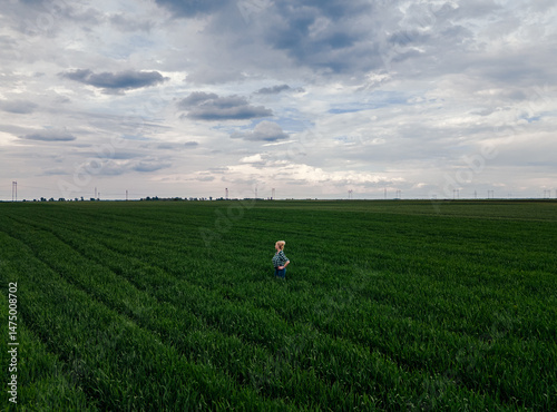 Wallpaper Mural Aerial view of adult female farmer standing in green wheat field examining crop. Torontodigital.ca