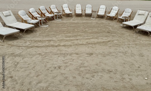 A circular arrangement of white beach loungers and padded chairs on sandy terrain, creating a serene, inviting gathering space by the beach.