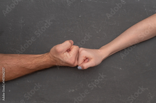 Fotografía Male fist pressing against female fist on gray background, intense physical tension symbolizing conflict and opposing