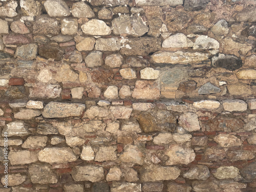 Old brick wall with rough layers of plaster, close-up. Texture for grunge background. Plaster with dirty stains and watermarks, different bricks. Deterioration of the outer wall.
