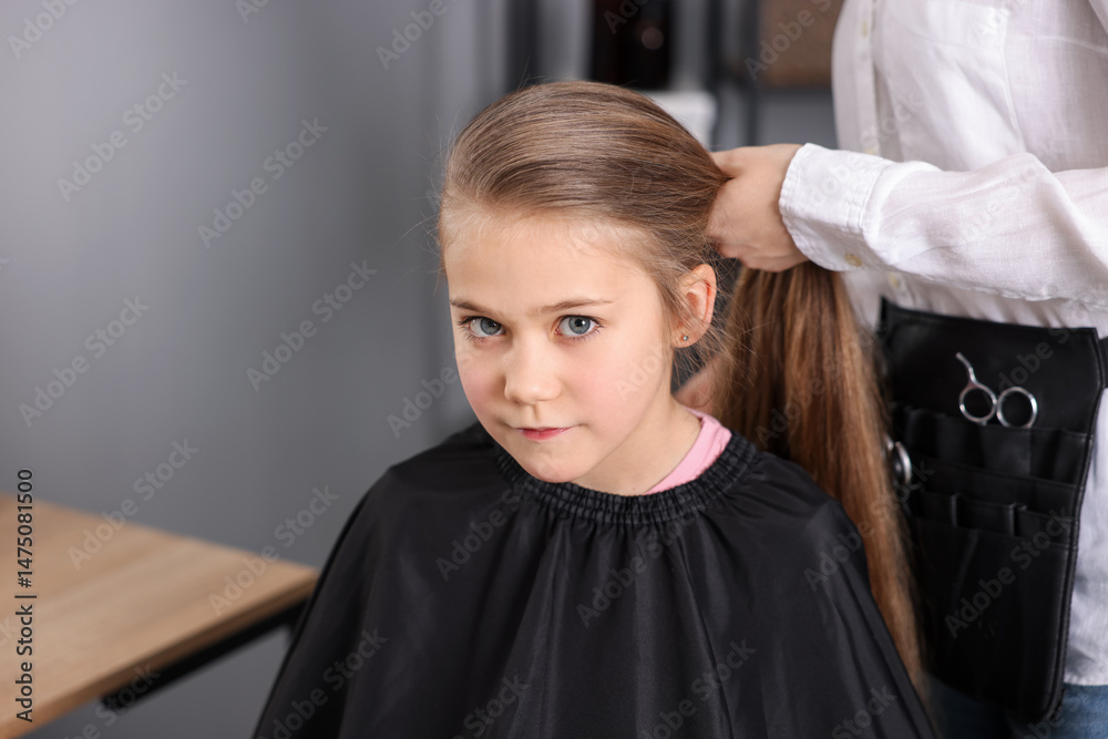 Fototapeta premium Hairdresser doing girl's hairstyle in salon, closeup