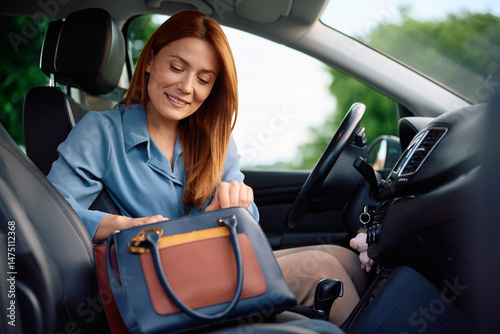 Photos Happy woman looking at something in her handbag while driving car