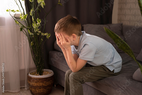 Insulted upset one sad little boy sitting on the couch. Child abuse. Anxiety and stress. Bullying concept, depressive stress or disappointment, sadness.
