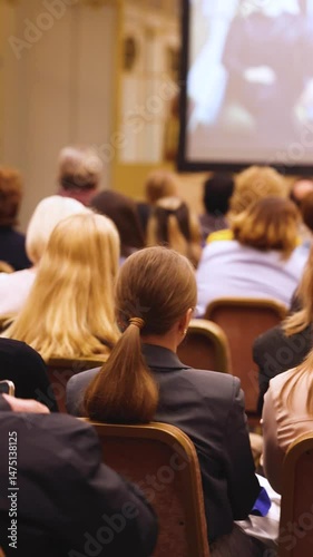Female audience at the symposyum meeting, participants attendees in conference room hall listens to lecturer, group of women on a medical congress together listen to speaker on a stage at master-class
