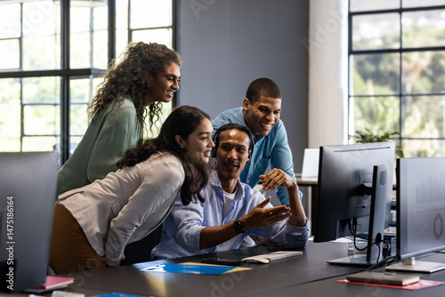 Collaborating in office, diverse team discussing project ideas around computer