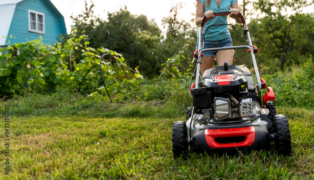 Fototapeta premium Woman with lawn mower in the garden