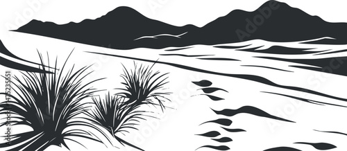 Black and white desert landscape with footprints in sand, sparse plants, and distant mountains