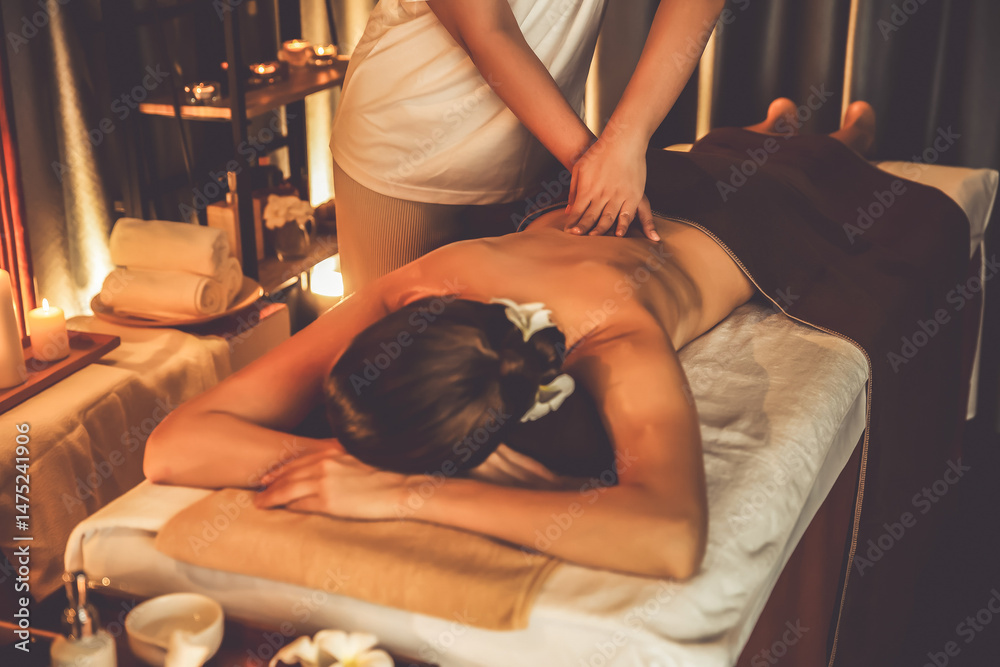 Obraz premium Caucasian woman customer enjoying relaxing anti-stress spa massage and pampering with beauty skin recreation leisure in warm candle lighting ambient salon spa at luxury resort or hotel. Quiescent