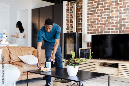 Man setting cake on table in modern living room, preparing for celebration