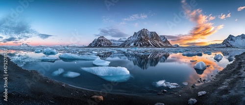 Panoramic view of a serene arctic landscape at sunset, featuring ice floes, calm water, and snow-capped mountains reflecting in the water.