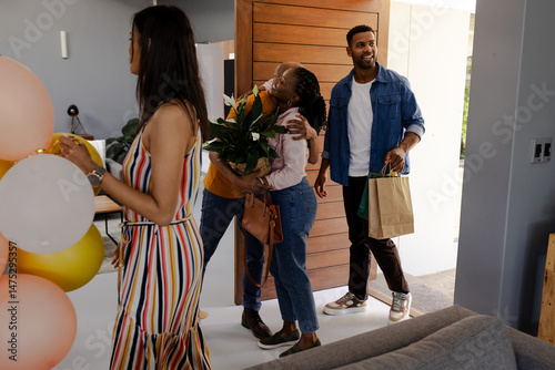 Friends arriving at home with gifts and flowers, ready to celebrate together