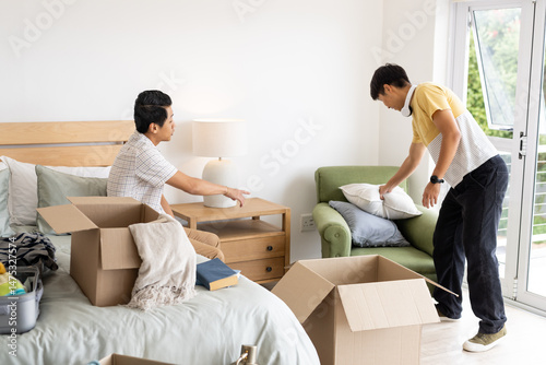 Friends unpacking boxes and organizing bedroom, creating cozy living space together