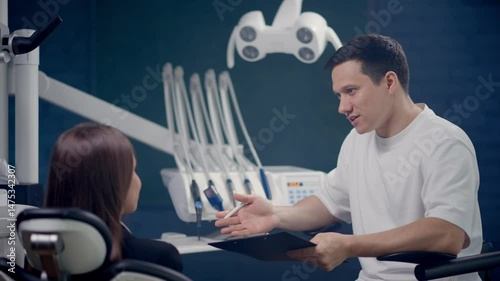 In a sleek, modern dental office, a dentist explains the necessary treatment options to the patient comfortably seated