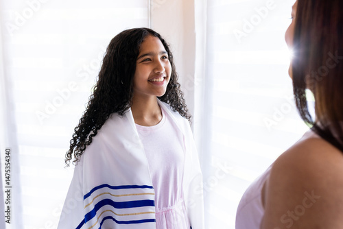Photos Young girl wearing prayer shawl smiling at woman during bar mitzvah