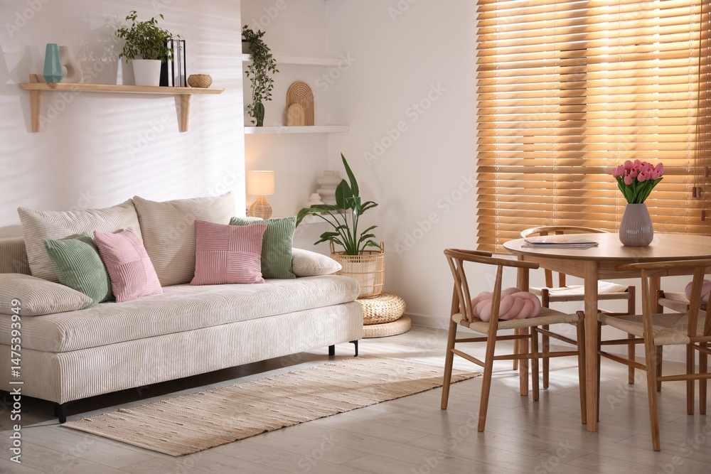 Fototapeta premium Stylish dining table with chairs and comfortable sofa in room. Interior design