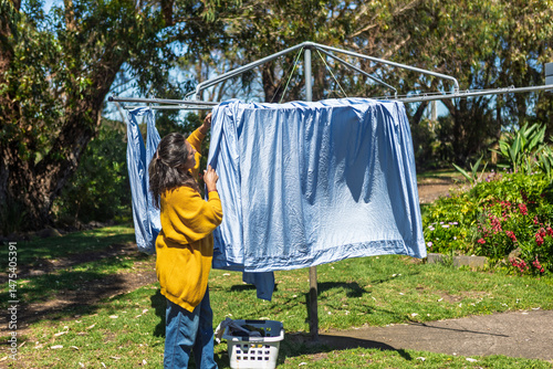 Woman doing laundry in her Australian backyard, hanging clothes