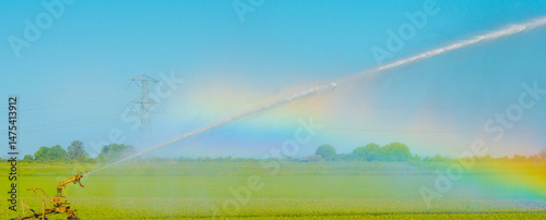 Irrigation equipment in an agricultural field causing a rainbow and watering dry land in springtime, Almere, Flevoland, The Netherlands, May 12, 2025
