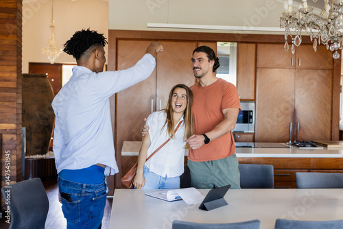 Real estate agent showing happy couple new home in modern kitchen