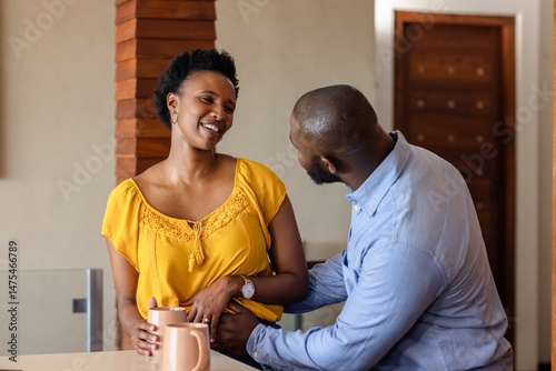 Couple enjoying morning coffee together, sharing laughter and affection at home