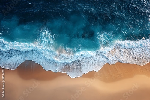 Aerial view of turquoise ocean waves crashing on golden sandy beach
