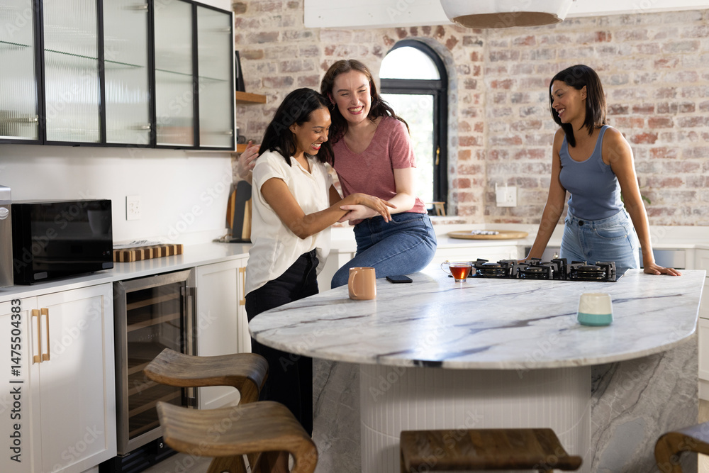Obraz premium Laughing together in modern kitchen, three young women enjoy casual moment