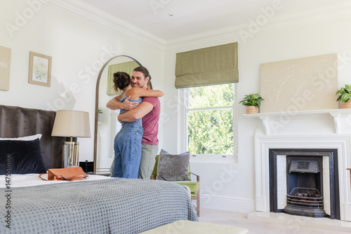 Couple embracing in cozy bedroom, enjoying intimate moment by window