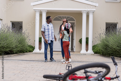 Outside home, African American family spending time together with bicycle in foreground