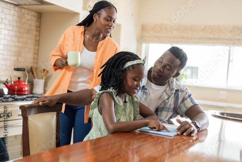Family enjoying quality time at home, daughter reading book with parents