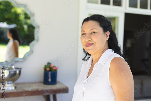 Smiling woman enjoying outdoor gathering, standing near table with flowers