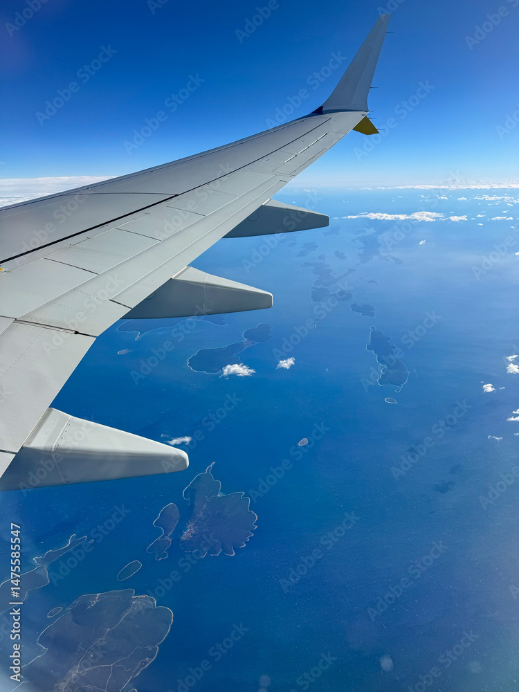 AERIAL: View from an airplane in flight over islands scattered across Adriatic Sea. Aeroplane wing frames stunning Mediterranean landscape under cloudless sky. Amazing views while traveling by plane.