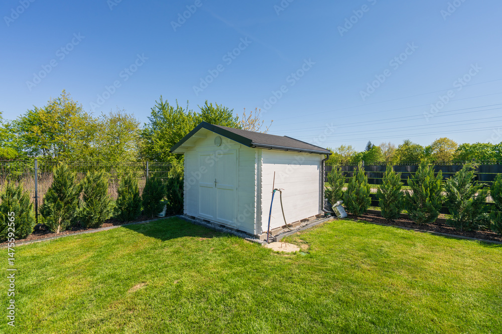 Wooden painted in white shed in the garden under clear blue sky