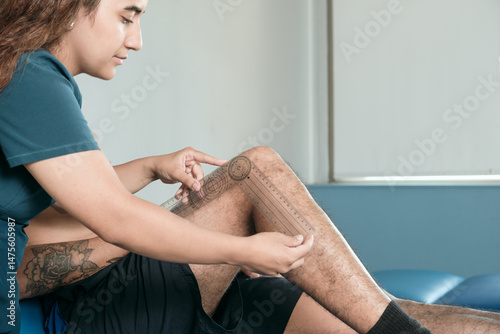 Young Female Therapist Treating Patients Knee Injury in Rehabilitation Clinic