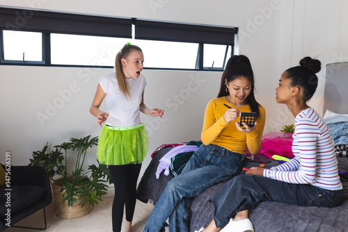Teen girls enjoying makeup session at home, laughing and sharing beauty tips