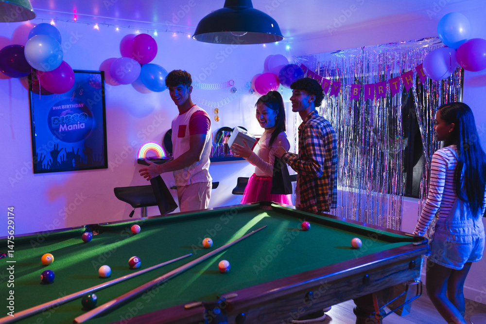 Fototapeta premium Teenagers enjoying birthday party with pool table and colorful decorations indoors
