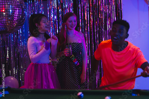 Teens enjoying lively birthday party with pool table and disco ball