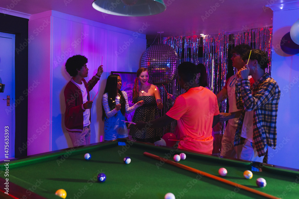 Naklejka premium Teenagers celebrating around pool table with colorful lights and festive decorations
