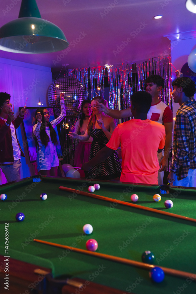 Fototapeta premium Celebrating around pool table, teenagers with drinks in festive party atmosphere