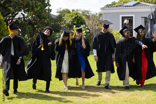 Graduating students in caps and gowns celebrating joyfully outdoors together