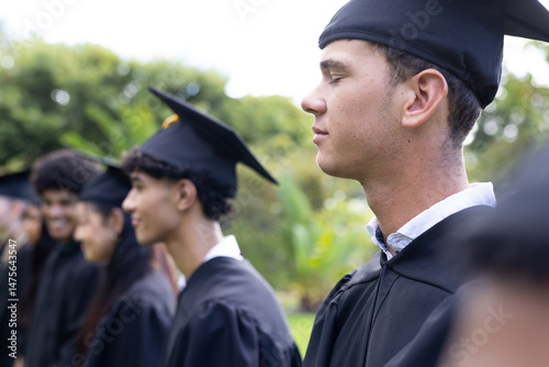 Graduating students in caps and gowns celebrating outdoors with joyful expressions