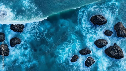 Ocean's Embrace: Aerial shot of the ocean waves crashing against dark rocks, creating a mesmerizing dance of water and stone. Evoking a sense of vastness and the raw beauty of nature.