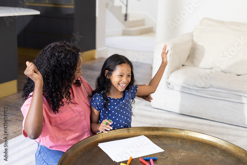 Mother and daughter drawing together at home, sharing joyful moments