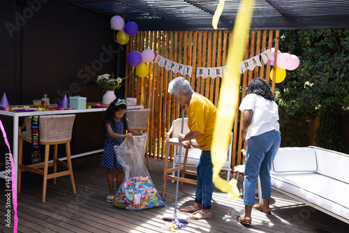 Celebrating birthday outdoors, family decorating with balloons and colorful streamers
