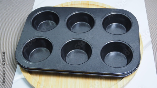 Close-up of an empty muffin tin with multiple round baking cups. Kitchen baking equipment photographed indoors.