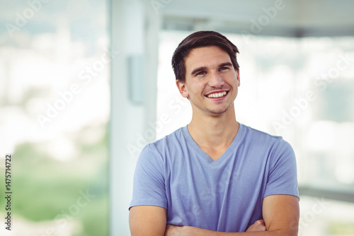 Smiling male in mid-20s standing with arms crossed in modern interior, featuring blurred cityscape Free Download Smiling male in mid-20s standing with arms crossed in modern interior, featuring blurred cityscape - GFXLoad