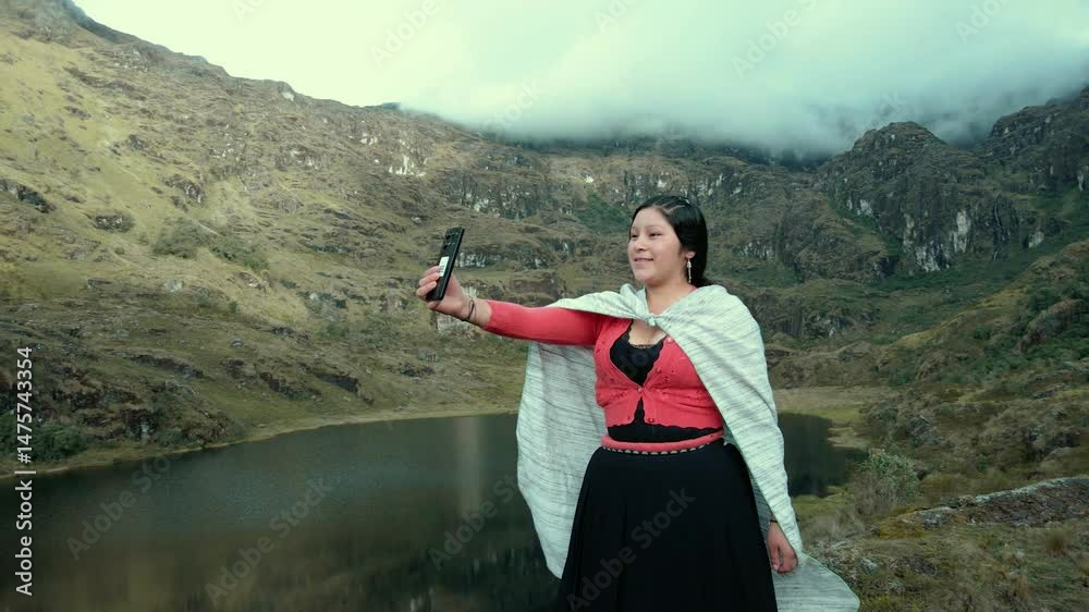 Video de una feliz y bonita campesina en una laguna hablando por un teléfono celular en los Andes peruanos. Mujer usando teléfono móvil.Quechua.Estilo de vida.