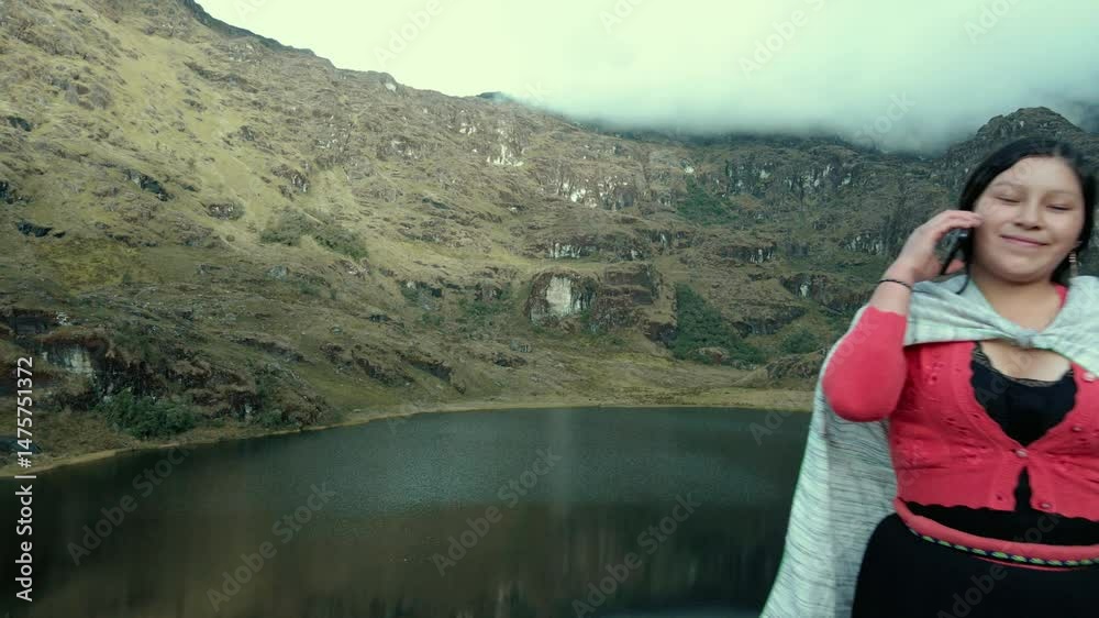 Video de una feliz y bonita campesina en una laguna hablando por un teléfono celular en los Andes peruanos. Mujer usando teléfono móvil.Quechua.Estilo de vida.